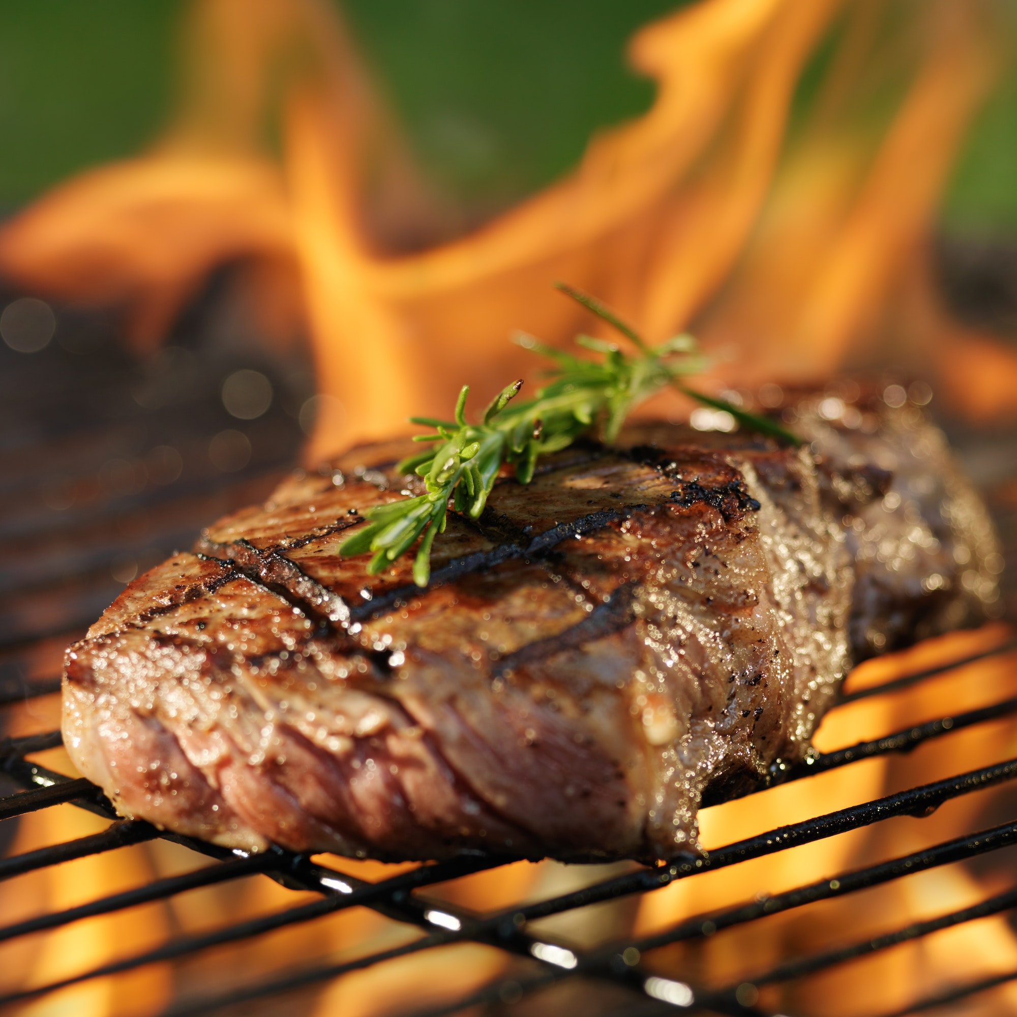 steak cooking over flaming grill